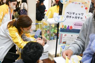 明治安田生命保険相互会社による、手のひらをかざして野菜の摂取量を測るベジチェックとガチャガチャのコーナー