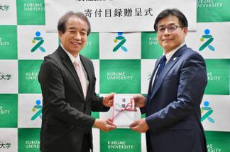 村上氏から内村理事長兼学長へAED寄付の目録が手渡されました