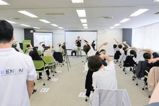 デモンストレーションを行う学生の動きを真似してストレッチ