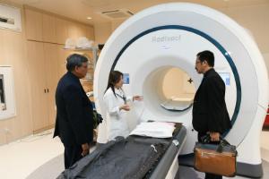 大学病院の放射線腫瘍センターを見学する一行と説明する淡河恵津世センター長