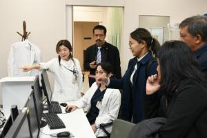 大学病院の放射線腫瘍センターを見学する一行と説明する淡河恵津世センター長