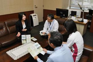 廣松病院長、大塚看護部長らにリーフレットについて説明する塩崎さん（左）
