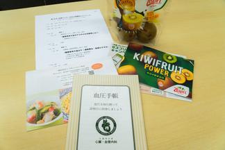 参加者に配布された血圧手帳（久留米大学心臓・血管内科作成）、ビタミンCや食物繊維、カリウムなどが豊富で間食に適したキウイ