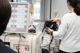 検査用の帽子をかぶり、ディスプレイの前で画面の指示に従いながら、課題に答えていきます。その際、脳血流の変化を測定します。
