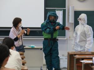 バイオテロを想定した除染活動のシミュレーション。レベルCの防護具(PPE)を一類防護具を着用した人に介助してもらって安全に着脱します。