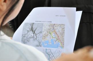 古地図と現在の地図を手に街を歩く学生