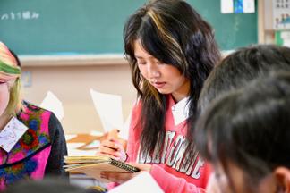 メモを取りながら発表を聞く学生