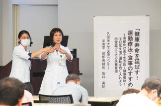 講演する 坂口氏と「輪っかテスト」で自身のふくらはぎを測る参加者
