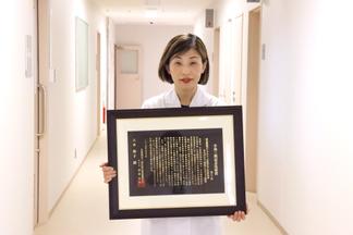 賞状を持つ八木朝子准教授