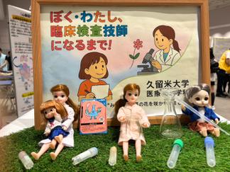 紙芝居の登場した白衣姿の人形たちが未来の検査技師を応援