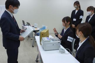 投票開始前に久留米市選挙管理委員会の職員から説明を受ける